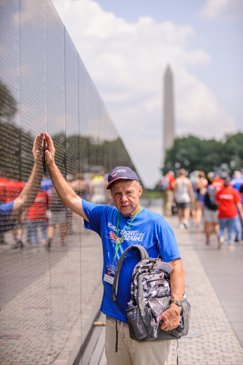 Honor Flight Veteran with Guardian next to American Flag