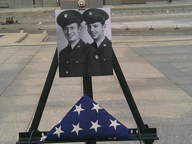 Easel holding a wartime portrait beside a folded flag at the World War II Memorial