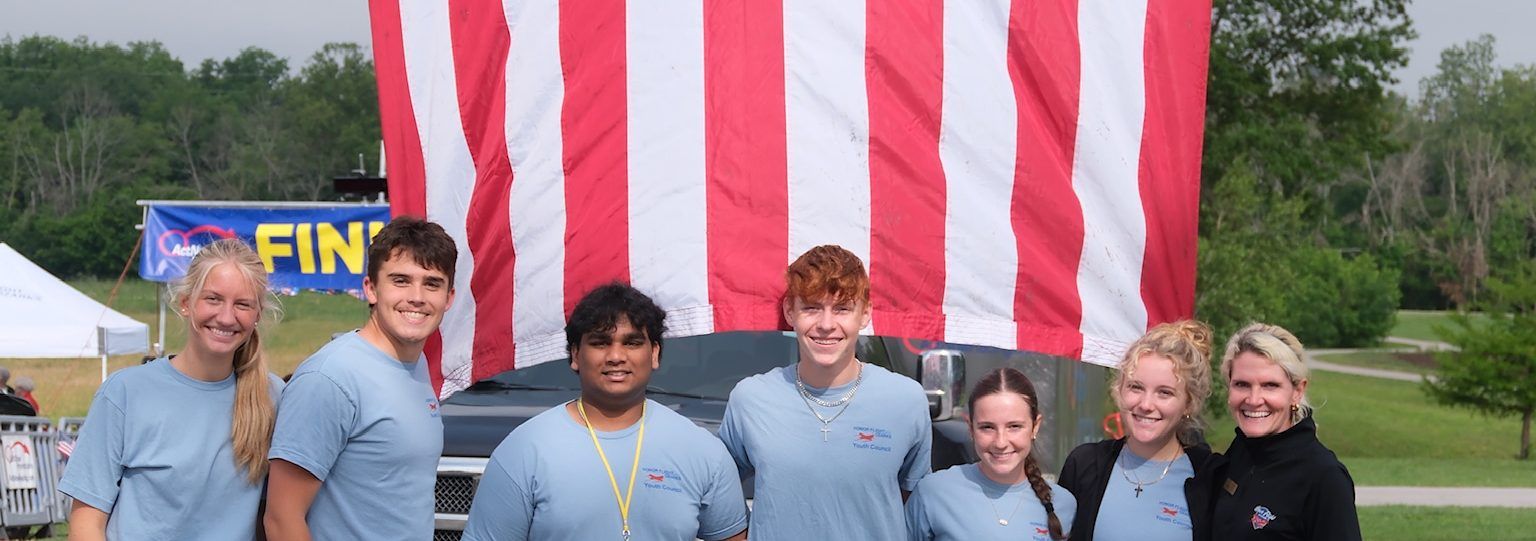 Honor Flight Youth Council members in front of a large American flag
