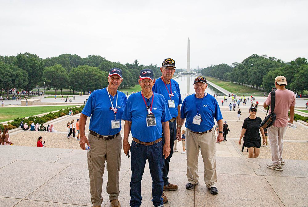 Four Honor Flight veterans on the National Mall with the Washington Monument behind them